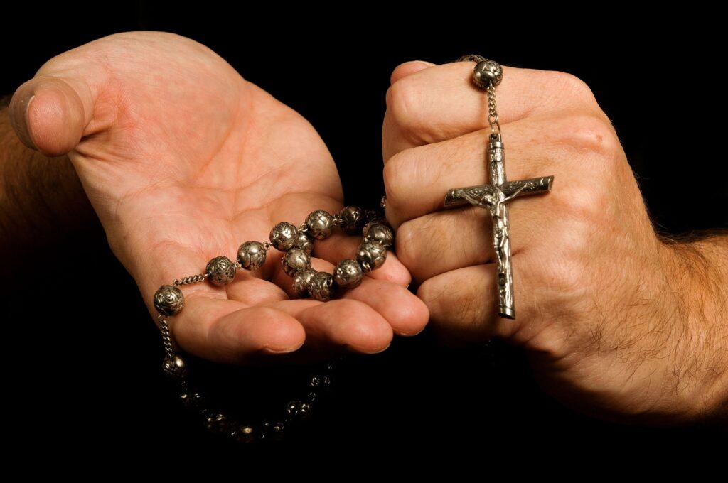 Closeup shot of hands holding a Christian Cross Pendant